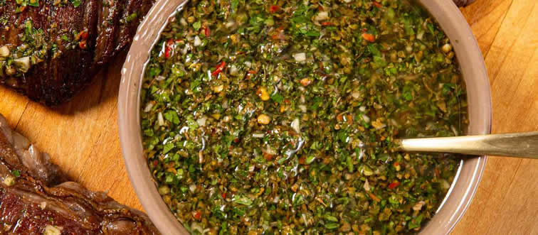 If you are setting up an Argentine barbecue, which iconic herb, garlic, vinegar, and oil sauce must be on the table?